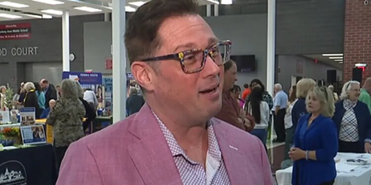 Chad Alan-Carr wearing glasses and pink suit during an interview