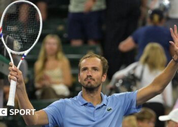 Daniil Medvedev holds up a tennis racquet