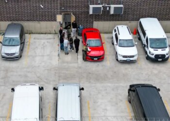 Detainees put items into clear plastic bags given to them by masked federal agents near an exterior door at the U.S. Immigration and Customs Enforcement holding facility in Broadview on Oct. 13, 2025. (Stacey Wescott/Chicago Tribune)