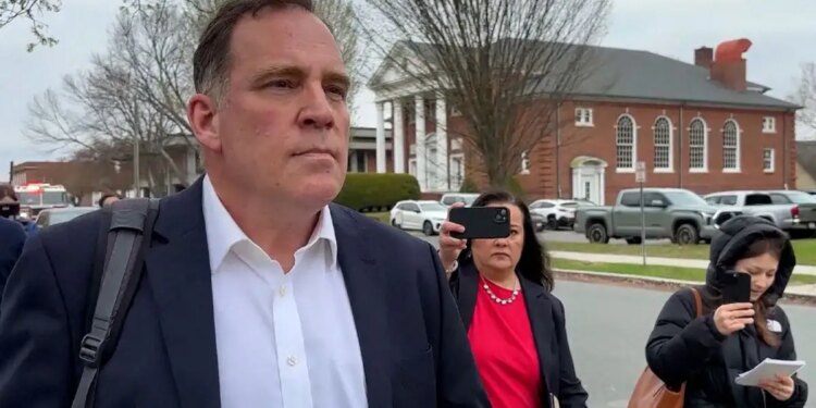 Former teacher walking into a court room with press behind him