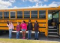 Mississippi middle school students stand next to a bus