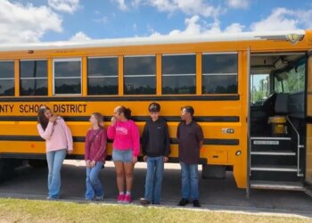 Mississippi middle school students stand next to a bus