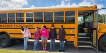 Mississippi middle school students stand next to a bus