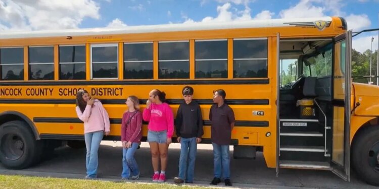 Mississippi middle school students stand next to a bus