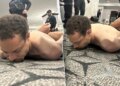 A suspect lying face down on the floor as law enforcement officers detain him