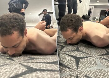 A suspect lying face down on the floor as law enforcement officers detain him