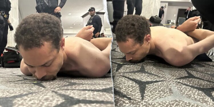 A suspect lying face down on the floor as law enforcement officers detain him