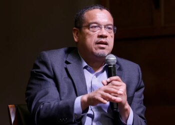 Minnesota Attorney General Keith Ellison speaking at a microphone indoors