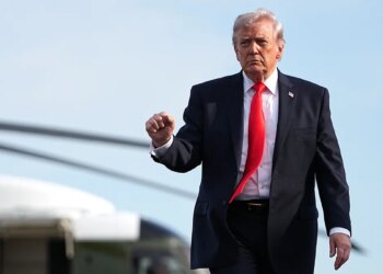 President Donald Trump walking from the Marine One helicopter toward Air Force One at an airport.