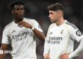 Real Madrid's Aurelien Tchouameni and Federico Valverde stand next to each other in a match, wearing the club's white kit