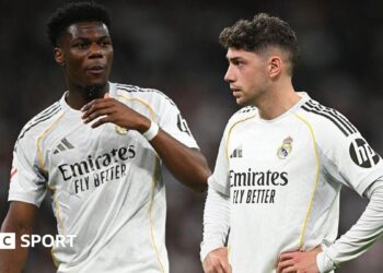 Real Madrid's Aurelien Tchouameni and Federico Valverde stand next to each other in a match, wearing the club's white kit
