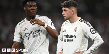 Real Madrid's Aurelien Tchouameni and Federico Valverde stand next to each other in a match, wearing the club's white kit