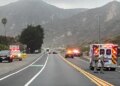 California Highway Patrol officers, an ambulance and emergency vehicles are seen at the scene of a fatal crash involving three bicyclists and a pickup truck on Pacific Coast Highway near Solimar Beach Road in Ventura County, with mountains in the background.
