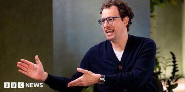 Dario Amodei, co-founder and chief executive officer of Anthropic, speaking during an interview in a room decorated with plants