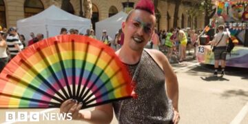 Man holds a pride fan