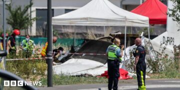 Emergency service workers speak to each other as the attend a light aircraft crash site