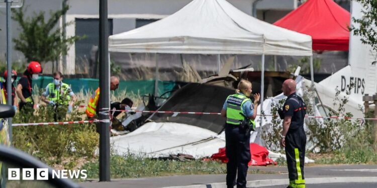 Emergency service workers speak to each other as the attend a light aircraft crash site