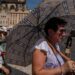 A woman with an umbrella shields herself from the sun in Prague's Old Town