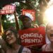 Tenant rights group members celebrating and cheering with sunshine and trees in the background in East Harlem, New York City.