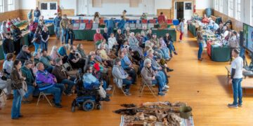 Dozens of people, seated in multiple rows of chairs, gather for a presentation during Talbot County's Native American Heritage and Artifact Day, held in February. Some Native Americans artifacts are seen on the floor, near the small crowd.