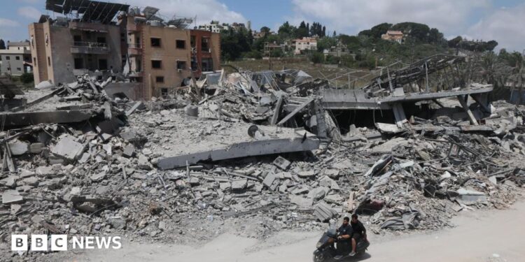 A man riding a motorcycle past destroyed buildings in the village of Mayfadoun, southern Lebanon (23 June 2026)