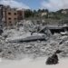 A man riding a motorcycle past destroyed buildings in the village of Mayfadoun, southern Lebanon (23 June 2026)