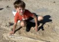 Boy standing over fossil in dirt