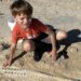 Boy standing over fossil in dirt