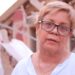 Zuly Marín, dressed in a white shirt and black glasses, stares into space.