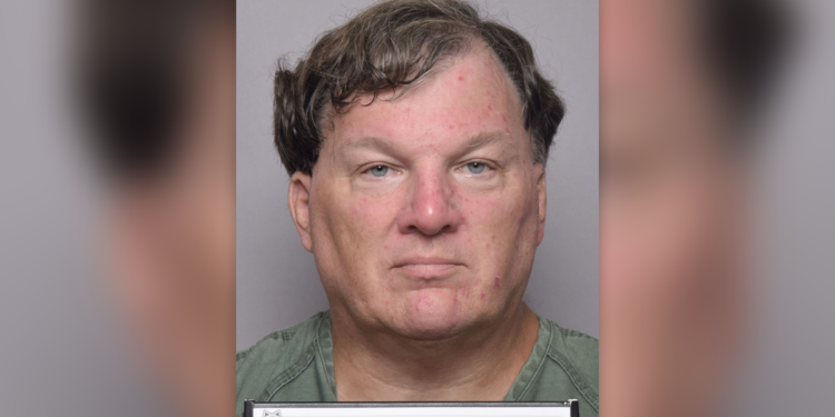 Rex Heuermann has wavy borwn hair in his latest mugshot, wearing a green shirt and holding placard that reads Suffolk County Sheriff's Office