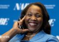 Lisa D. Cook, a member of the Board of Governors of the Federal Reserve, smiles while holding her hand against her face. She is wearing a blue suit and speaks at The Capital Hilton during the 42nd annual National Association for Business Economics Economic Policy Conference on February 24, 2026 in Washington, DC.