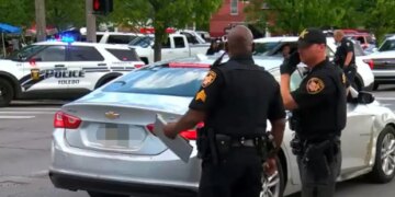 Police officers standing near vehicles at a crime scene in Toledo, Ohio