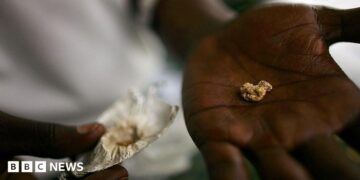 An individual holds a nugget of gold in his palm