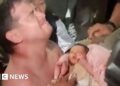 Emotional man holds baby wrapped in pink blanket