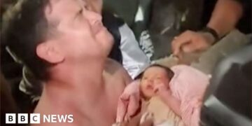 Emotional man holds baby wrapped in pink blanket