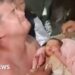 Emotional man holds baby wrapped in pink blanket