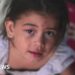 A young girl with a bruised face looks into the camera