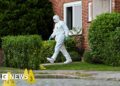 A man in a white hazmat suit walks out of a house in Stade, Germany.