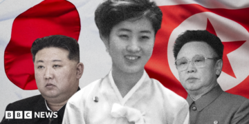 A young Ko Yong Hui at the centre, Kim Jong Un on the left, and Kim Jong Il on the right. A Japanese flag (L) and a North Korean flag behind the trio