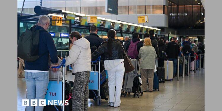 People wait at the top of escalators with luggage and checking phones at the Eurostar terminal at St Pancras in London, in December. The Eurostar sign can be seen in the background.