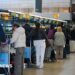 People wait at the top of escalators with luggage and checking phones at the Eurostar terminal at St Pancras in London, in December. The Eurostar sign can be seen in the background.