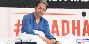 Activist Sonam Wangchuk - wearing a blue shirt - looks sideways as he sits on a hunger strike in Delhi