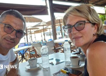 Karovic Ljubisa and his wife Svetlana Grković, smiling for a photo in a bar which appears to be at a holiday resort