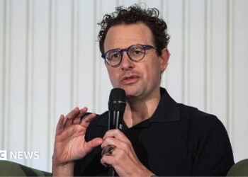 Anthropic chief executive Dario Amodei speaks through a microphone during a summit