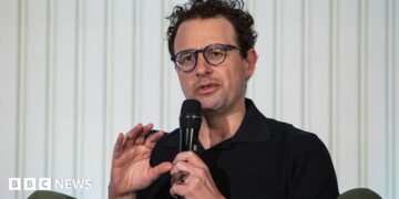 Anthropic chief executive Dario Amodei speaks through a microphone during a summit