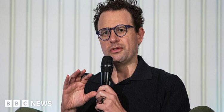 Anthropic chief executive Dario Amodei speaks through a microphone during a summit