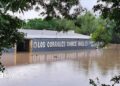 Floodwaters are seen engulfing the Rodeo Los Corrales Dance Hall in Comfort. Trees sit around the hall.