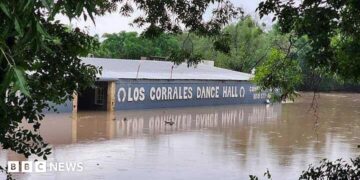Floodwaters are seen engulfing the Rodeo Los Corrales Dance Hall in Comfort. Trees sit around the hall.