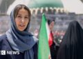Nawal wears a lose blue hijab and abayah as she reports from the Grand Mosalla in Tehran