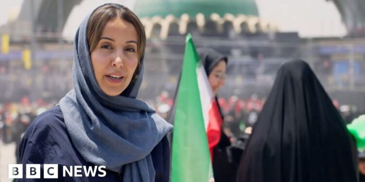 Nawal wears a lose blue hijab and abayah as she reports from the Grand Mosalla in Tehran